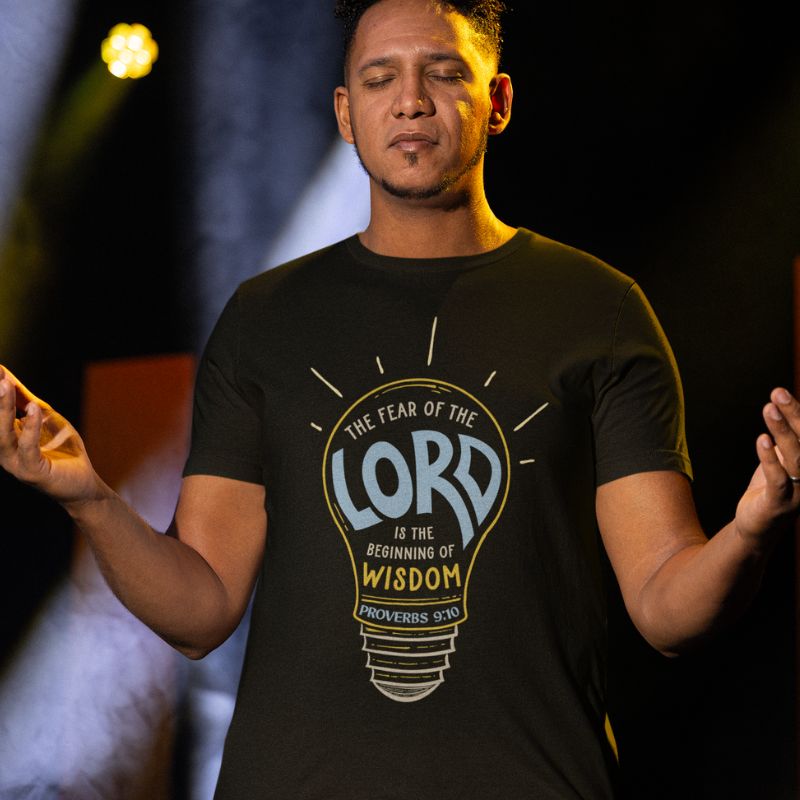 Hispanic man wearing a black Christian shirt. The design is a lightbulb, with text inside, that says, &quot;The fear of the Lord is the beginning of wisdom - Proverbs 9:10&quot;