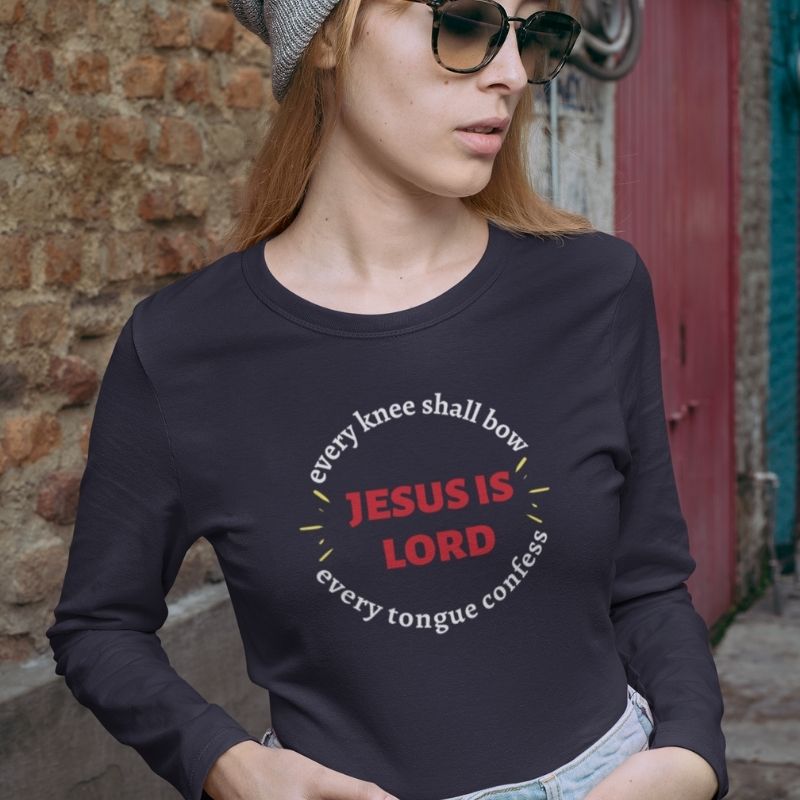 White woman wearing black Christian unisex T-shirt that says in a circle &quot;Every knee shall bow, every tongue confess&quot; with &quot;Jesus is Lord&quot; in the middle