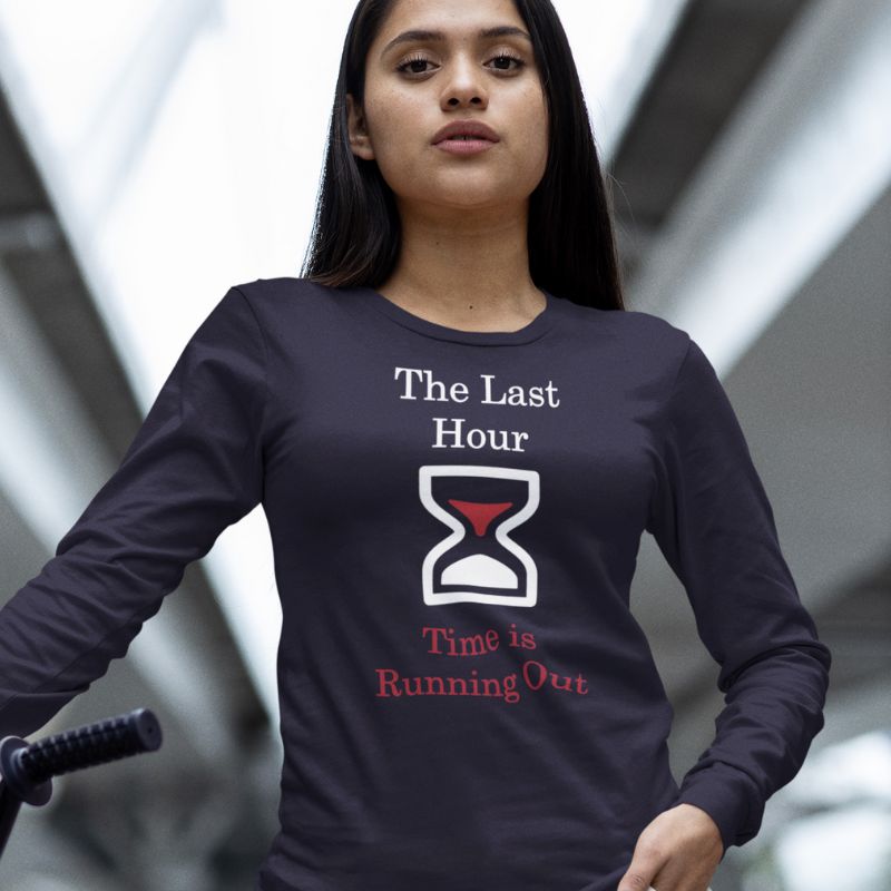 Hispanic woman wearing a navy Christian shirt. The shirt has a large hourglass icon in the middle. Above the hourglass, text says &quot;The Last Hour&quot; and below the hourglass, it says &quot;Time is Running Out&quot;.