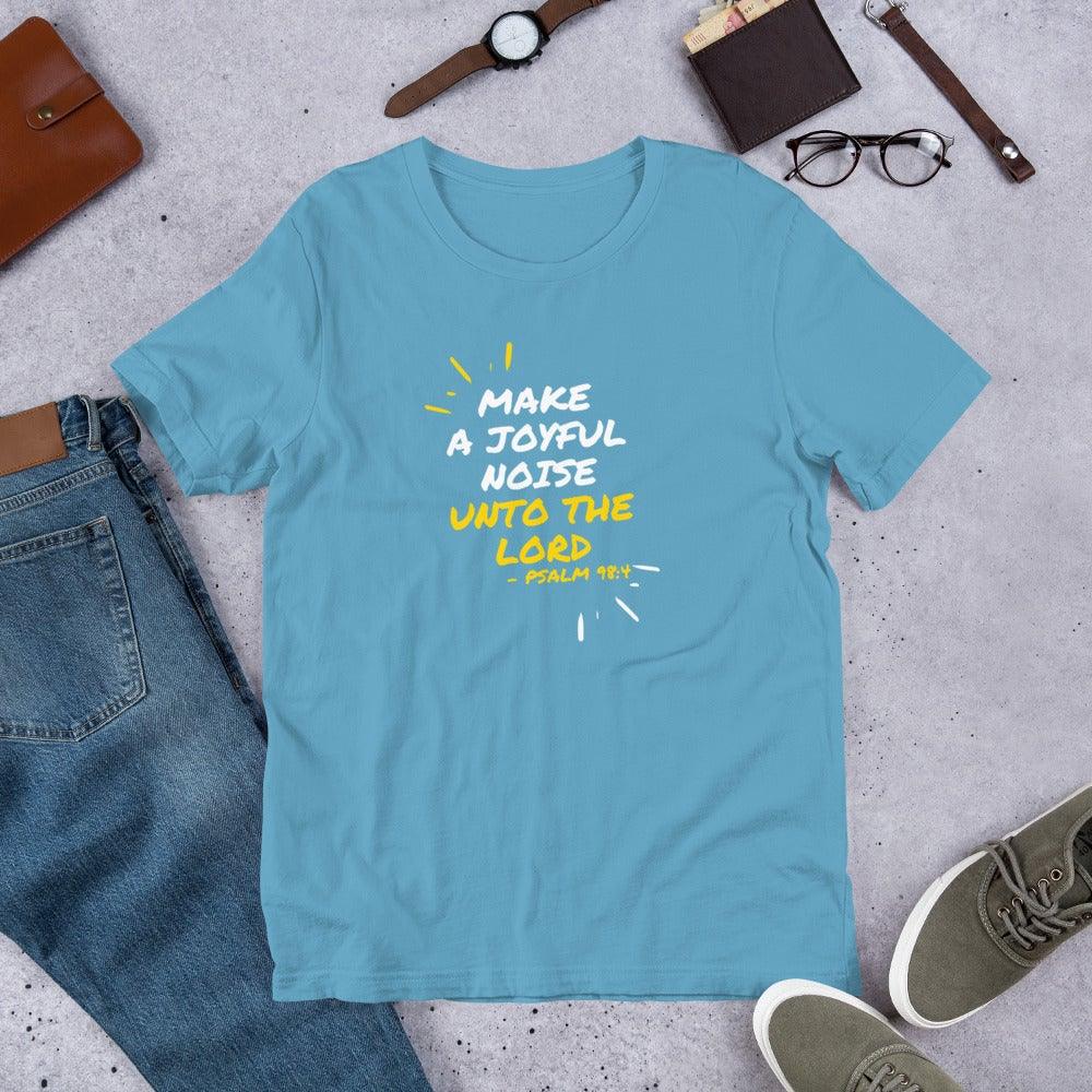 Flatlay of a blue Christian t-shirt that says &quot;Make joyful noise unto the Lord&quot; with &quot;Pslam 98:4 underneath&quot;. Surrounding the text, there are lines that show movement or music.